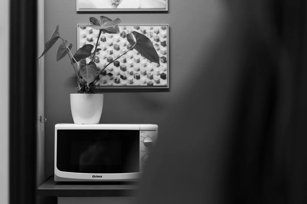 Kitchenette de escritório contemporânea na Lava com um micro-ondas elegante e uma planta em vaso, simbolizando a combinação de conveniência moderna e elementos naturais no nosso espaço de trabalho de web e branding.