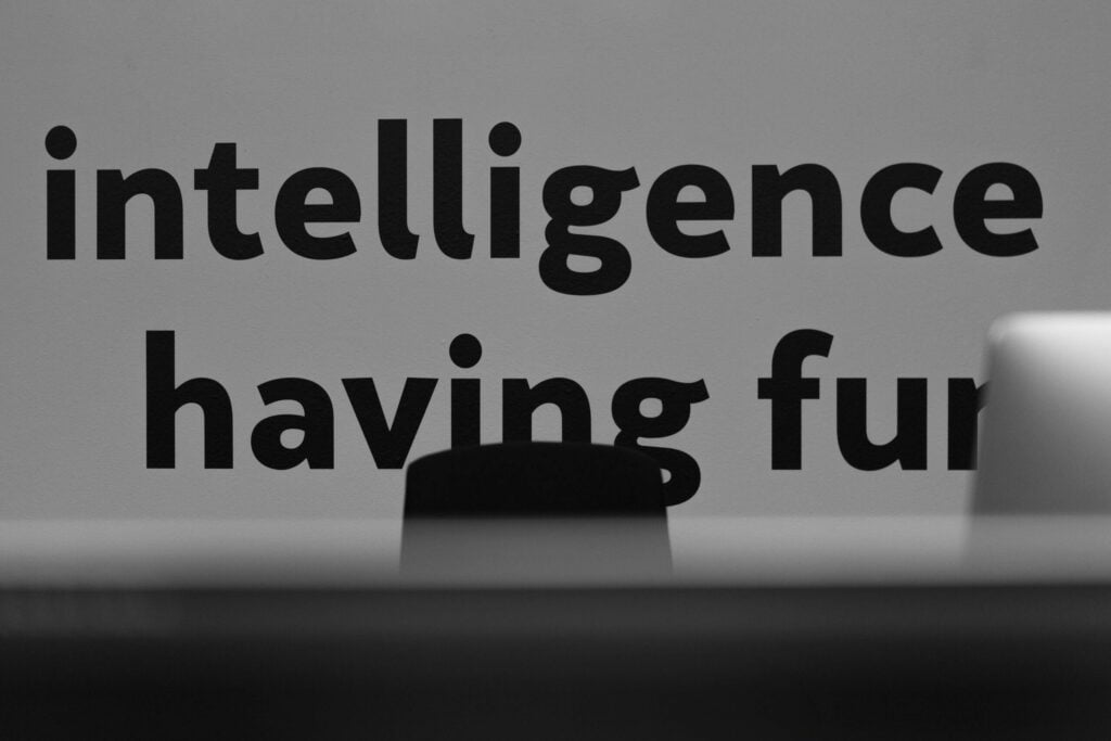 Visão aproximada da frase motivacional ‘intelligence having fun’ numa parede do escritório da Lava, incorporando o ethos da empresa de trabalho inteligente e agradável em web e branding.