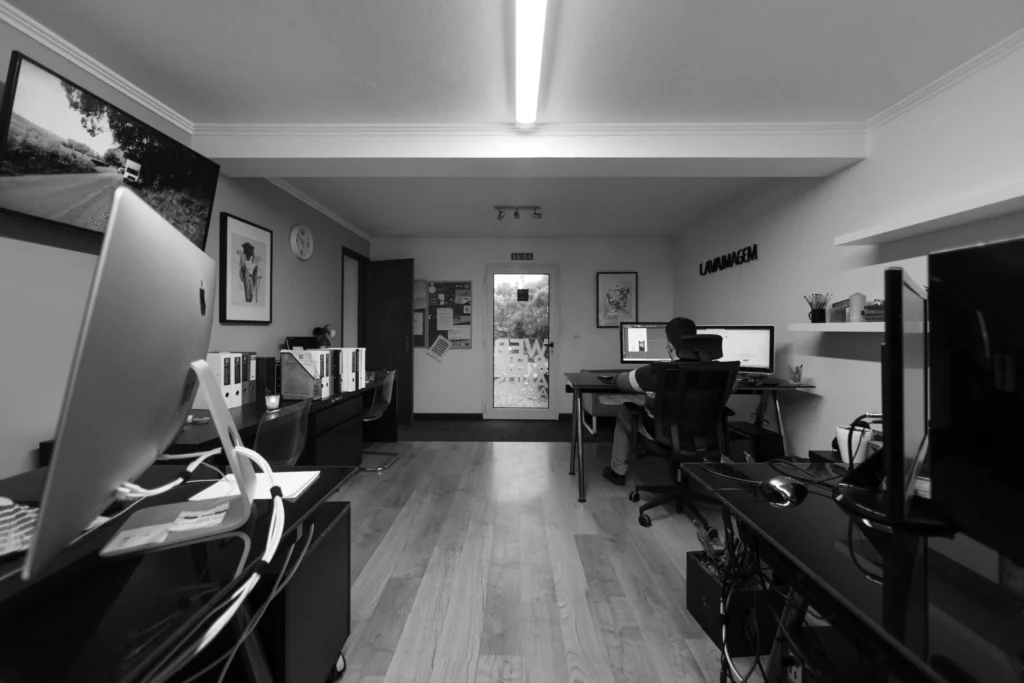 Espaço de escritório moderno e monocromático na Lava, exibindo uma área de trabalho limpa e organizada com computadores e cadeiras ergonômicas, refletindo nosso espaço de trabalho profissional de web e branding.